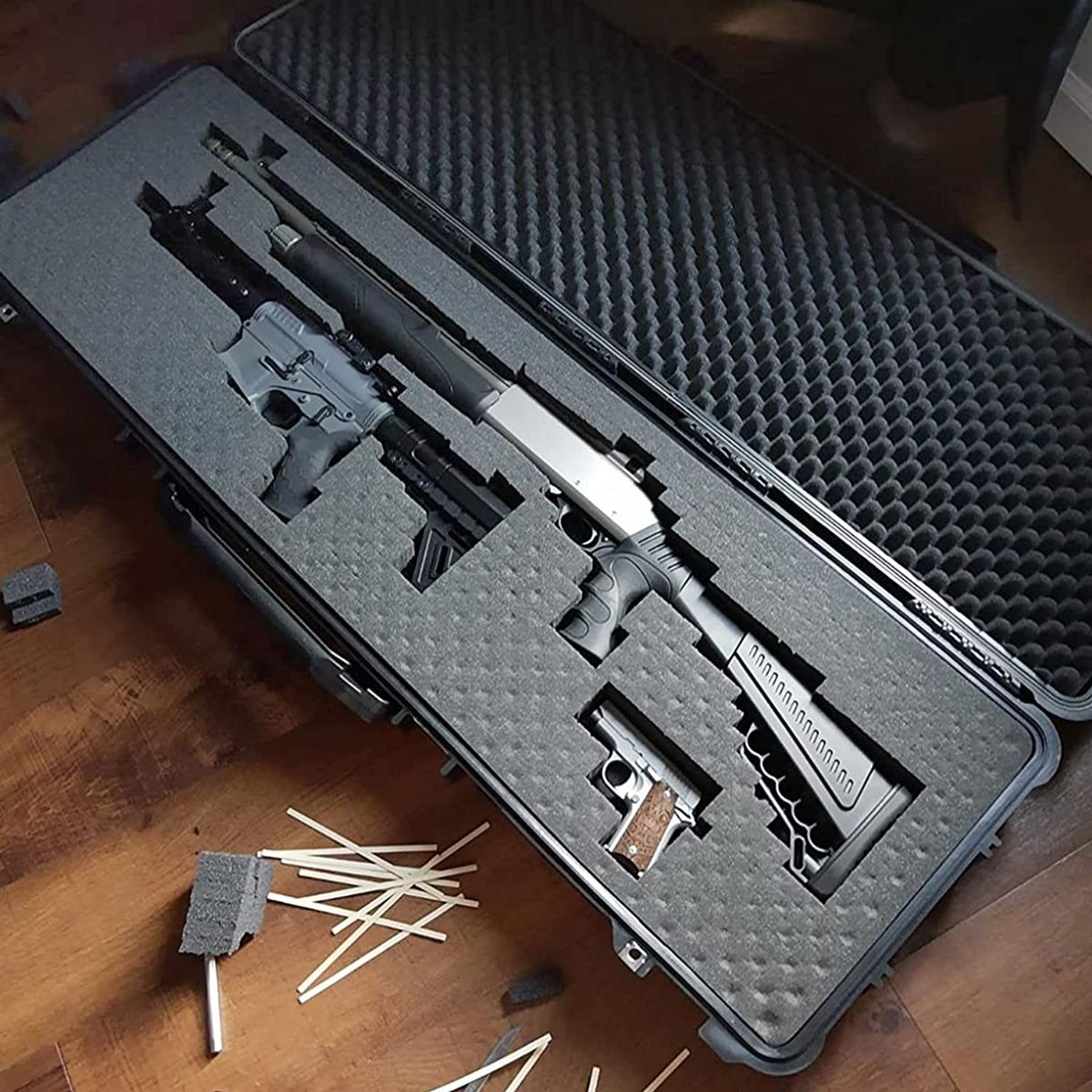 A tactical gun case with a shotgun with a pistol grip stock, a pistol, and a AR15 pistol all in one case.