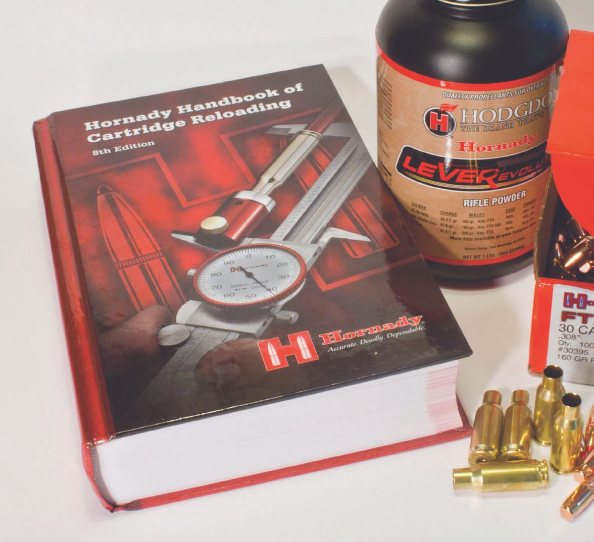 A Hornady manual with a pound of rifle powder and unprimed .308 brass and bullets.