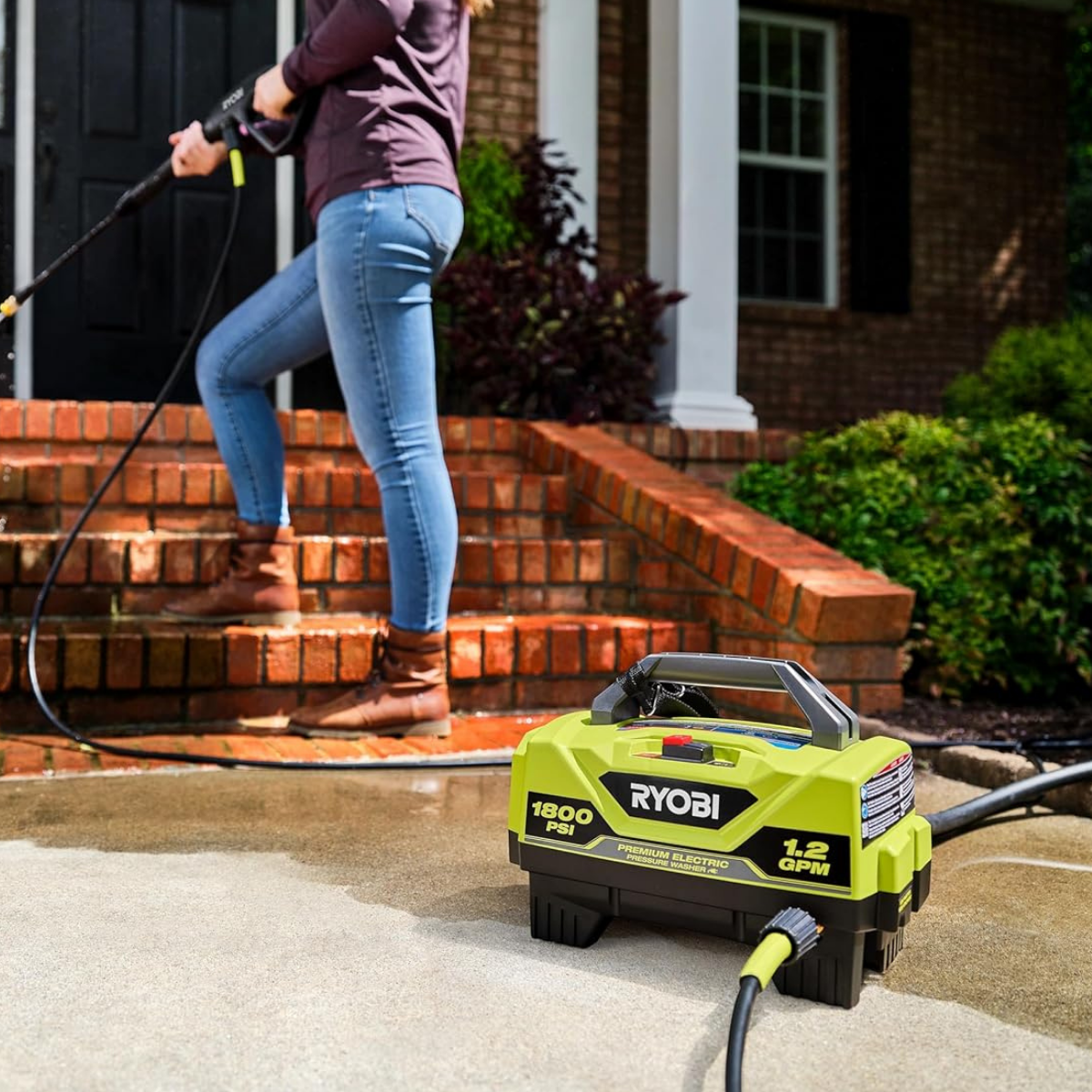 A woman cleaning a porch with an electric pressure washer from Ryobi