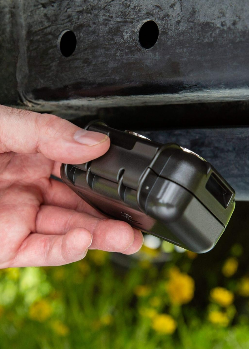 A man placing a small magnetic box to a trailer for GPS tracking.