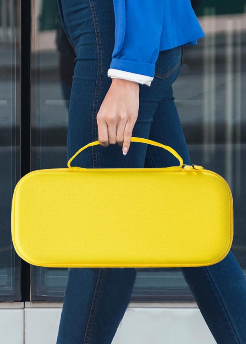 A woman carrying a PlayStation Portal in a bright yellow Portal case.