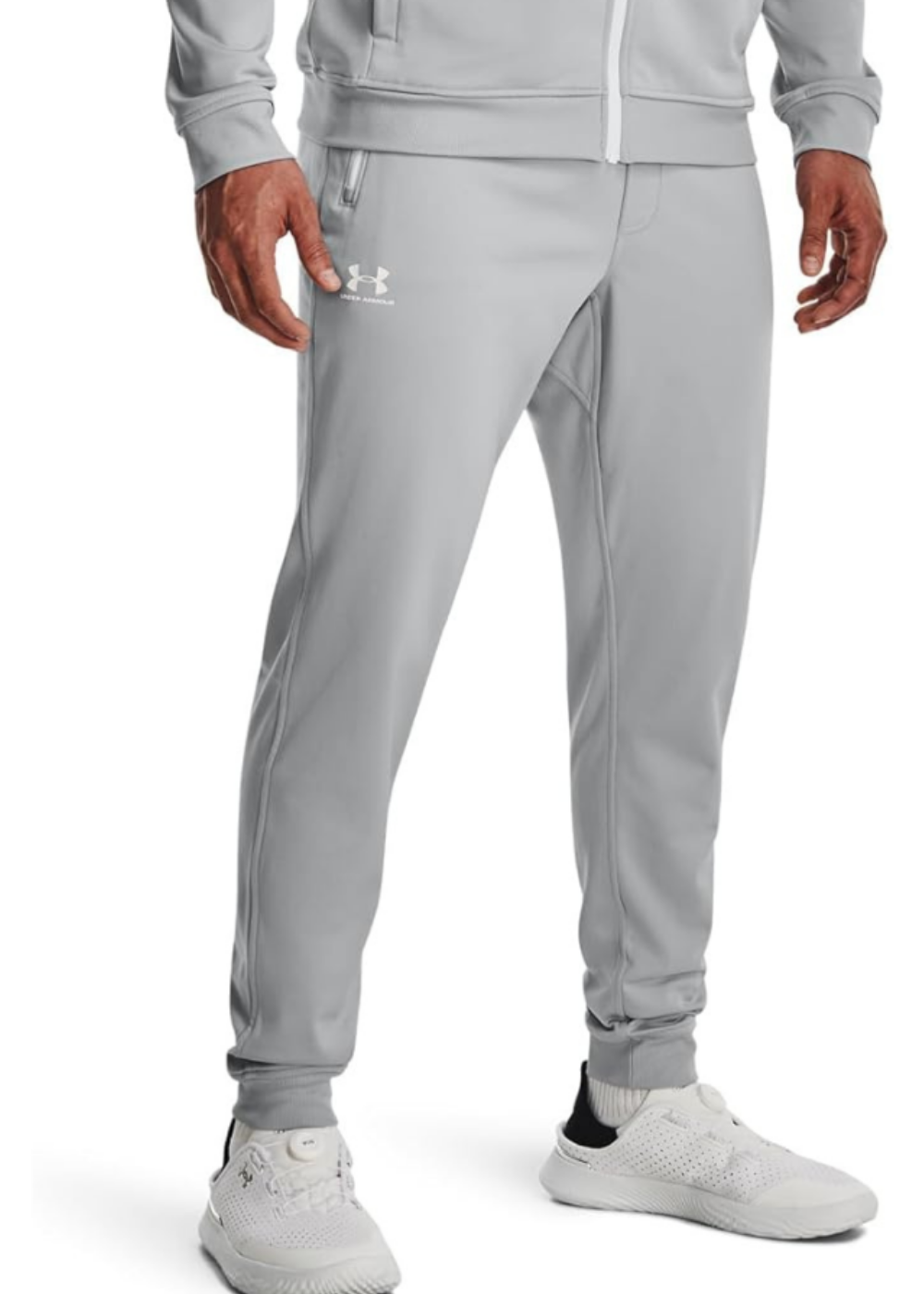 A close up of a man wearing gray sweats and white shoes from Under Armour