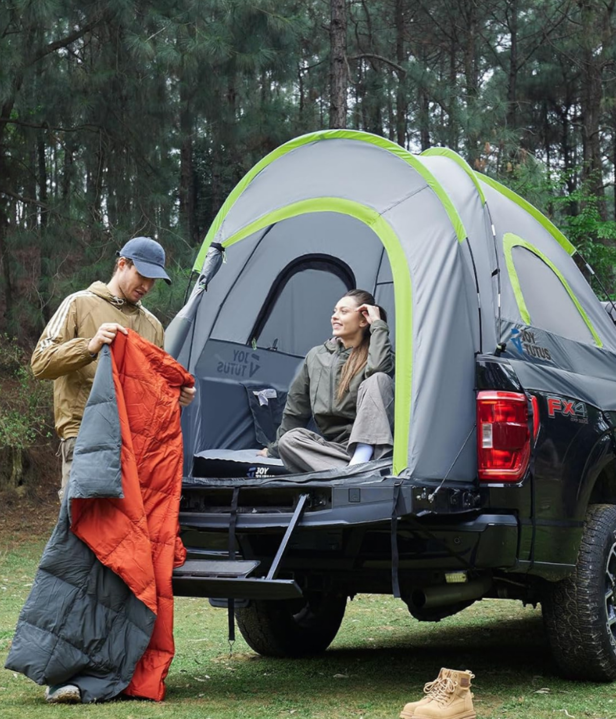 A man and woman at the back of a truck with a camper bed.